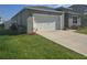 Exterior view of home with green grass, a driveway and white garage door at 1596 Park Side Ave, Kissimmee, FL 34744