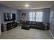 This spacious living room boasts a neutral-colored tile flooring and large TV at 1596 Park Side Ave, Kissimmee, FL 34744