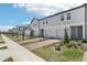 Row of two-story townhomes featuring light gray siding, white trim, individual garages, and brick driveways at 16395 Bird Of Paradise Ave, Clermont, FL 34714