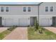 Exterior view of modern two-story townhomes featuring individual garages, brick driveways, and landscaped front yards at 16395 Bird Of Paradise Ave, Clermont, FL 34714