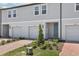 Exterior view of modern townhomes featuring individual garages, brick driveways, and landscaped front yards at 16395 Bird Of Paradise Ave, Clermont, FL 34714