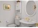 Cozy powder room with white fixtures, a decorative mirror and ornate gold faucet at 1640 N Atlantic Ave, New Smyrna Beach, FL 32169