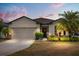 Charming single-story home with a two-car garage, manicured lawn, and a welcoming front entrance at 17500 Butterfly Pea Ct, Clermont, FL 34714