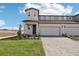 New two-story townhome featuring a gray exterior, a two-car garage, and a beautiful lawn with green grass at 1805 Archer Dr, Minneola, FL 34715