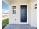 Covered front porch with a stylish door, complemented by a lantern-style light fixture and gray paver flooring at 1805 Archer Dr, Minneola, FL 34715