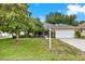 Charming single-story home featuring a two-car garage and lush front lawn with mature landscaping under a sunny blue sky at 26807 Bull Run, Leesburg, FL 34748