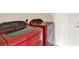 Laundry room with modern red washer and dryer adjacent to white door at 26807 Bull Run, Leesburg, FL 34748