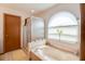 Bathroom featuring a soaking tub and shower and arched window at 2712 Rolling Broak Dr, Orlando, FL 32837