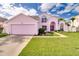 Charming pink two-story home with a well-manicured lawn and a two-car garage at 2712 Rolling Broak Dr, Orlando, FL 32837