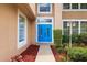 Close-up of a striking blue double front door surrounded by manicured landscaping and a decorative exterior lamp at 3468 Woodley Park Pl, Oviedo, FL 32765