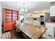 Dining area open to the kitchen with a large wooden table, built-in hutch, and modern lighting fixture at 398 Rose St, Umatilla, FL 32784