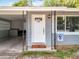Inviting front entrance with a decorative white door, stylish overhead light fixture, and cozy carport space at 398 Rose St, Umatilla, FL 32784