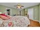 View of a bedroom with green walls, ceiling fan, floral bedding and hardwood floors at 5102 Monticello Heights Ln, Oviedo, FL 32765