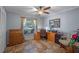 Bedroom with a window providing natural light, ceiling fan, tile flooring, and wooden desk at 5583 Miles Dr, Port Orange, FL 32127