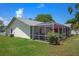 Exterior shot of the home showing a screened-in lanai with outdoor seating and well-maintained landscaping at 5583 Miles Dr, Port Orange, FL 32127