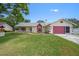 Charming single-story home featuring a well-manicured lawn, attached garage, and red trim at 5583 Miles Dr, Port Orange, FL 32127