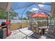Covered patio with string lights, a grill, and ample seating around a central table with umbrella at 5583 Miles Dr, Port Orange, FL 32127