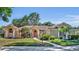 Stunning single-story home with a red front door, mature trees, and lush landscaping in a well-kept lawn at 605 W Palm Valley Dr, Oviedo, FL 32765