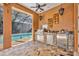 Outdoor kitchen featuring stainless grill and outdoor refrigerator overlooking the pool at 605 W Palm Valley Dr, Oviedo, FL 32765