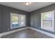 Bedroom featuring neutral gray walls, vinyl plank flooring, and bright natural light from two windows at 735 N Clara Ave, Deland, FL 32720