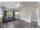 Bright living room boasts gray wood floors, neutral paint, ceiling fan, and gray couch at 735 N Clara Ave, Deland, FL 32720