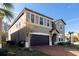 Two-story home featuring a neutral-tone exterior, dark garage door, and brick-paved driveway at 8924 Bengal Ct, Kissimmee, FL 34747