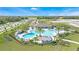 Aerial view of a community pool with lounge chairs, umbrellas, tables, and palm trees at 1596 Park Side Ave, Kissimmee, FL 34744