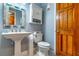 Charming powder room with pedestal sink, toilet, and decorative mirror with wooden door at 103 Golf Club Dr, Longwood, FL 32779