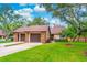 Charming home exterior featuring a well-manicured lawn, mature trees, and a two-car garage at 103 Golf Club Dr, Longwood, FL 32779