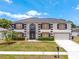 Inviting two-story home with a manicured lawn, complemented by lush greenery and a well-maintained front yard at 114 Shaddock Dr, Auburndale, FL 33823