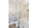 Neutral toned bathroom featuring gray-wood flooring, white cabinetry, and shower with floral curtain at 1161 Trappers Trail Loop, Davenport, FL 33896