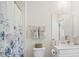 Neutral toned bathroom featuring gray-wood flooring, white cabinetry, and shower with floral curtain at 1161 Trappers Trail Loop, Davenport, FL 33896