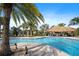 Inviting community pool with lush landscaping, tiki hut and lounge chairs for relaxing by the water at 1161 Trappers Trail Loop, Davenport, FL 33896