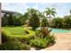 Beautifully landscaped backyard with a pool, lush greenery, and vibrant flowers creating a tranquil setting at 12030 Waterstone Loop Dr, Windermere, FL 34786