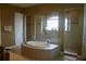 Luxurious bathroom featuring a large soaking tub, a glass-enclosed shower, and neutral tile at 12030 Waterstone Loop Dr, Windermere, FL 34786