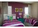 Colorful bedroom featuring two beds, vibrant purple walls, and patterned curtains for a playful ambiance at 12030 Waterstone Loop Dr, Windermere, FL 34786