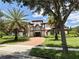 A beautiful two-story home featuring a tile roof, lush landscaping, palm trees and an arched entryway at 12030 Waterstone Loop Dr, Windermere, FL 34786