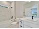 A luxurious bathroom boasts marble-look tiling, modern fixtures, and tub with shower; bright and airy at 13068 Sw 36Th Ct, Ocala, FL 34473