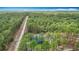 Aerial view of a home on a treed lot with a long gravel road leading to the home with some natural clearing at 13297 Sw 69Th Pl, Ocala, FL 34481