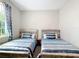 Bedroom with matching twin beds featuring blue striped bedding and bedside tables under a modern ceiling light at 13297 Sw 69Th Pl, Ocala, FL 34481