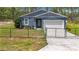 Charming blue single-story home with a white garage door and a black chain-link fence in the front yard at 13297 Sw 69Th Pl, Ocala, FL 34481