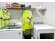 Bright laundry room features a modern washer and dryer with storage shelving and neon yellow high-visibility outerwear at 13297 Sw 69Th Pl, Ocala, FL 34481