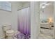 Bright bathroom featuring a toilet, shower with purple curtain, and a view of the bedroom at 14003 Hampshire Bay Cir, Winter Garden, FL 34787
