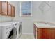 Laundry room with updated machines, wood cabinets and shelving, and a deep utility sink at 14003 Hampshire Bay Cir, Winter Garden, FL 34787