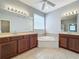 Bright bathroom with dual sinks, wood cabinets, a soaking tub, and tiled floors at 17146 Cypress Preserve Pkwy, Orlando, FL 32820