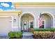 Welcoming front porch featuring an arched entryway, seating, and manicured landscaping at 1780 Southern Red Oak Ct, Ocoee, FL 34761