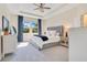 Bright main bedroom with a decorative ceiling fan, a tufted headboard, and natural light from the outdoor view at 1780 Southern Red Oak Ct, Ocoee, FL 34761