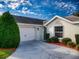 Single-story home with an attached garage, well-manicured bushes, and a driveway on a sunny day at 17816 Se 115Th Ct, Summerfield, FL 34491