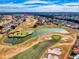 Expansive aerial view of a golf course featuring a scenic pond, manicured greens, and residential area at 17816 Se 115Th Ct, Summerfield, FL 34491