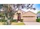 Single-story home with a well-maintained lawn, red door, two-car garage, and lush green foliage at 19756 Glen Elm Way, Orlando, FL 32833
